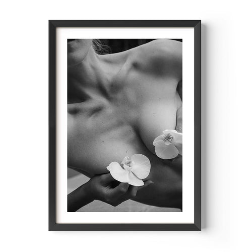Framed black-and-white photograph of a woman’s collarbone with white orchid flowers, styled in a Parisian interior with molding, mirror, and chair — by Britt Van der Meijden.