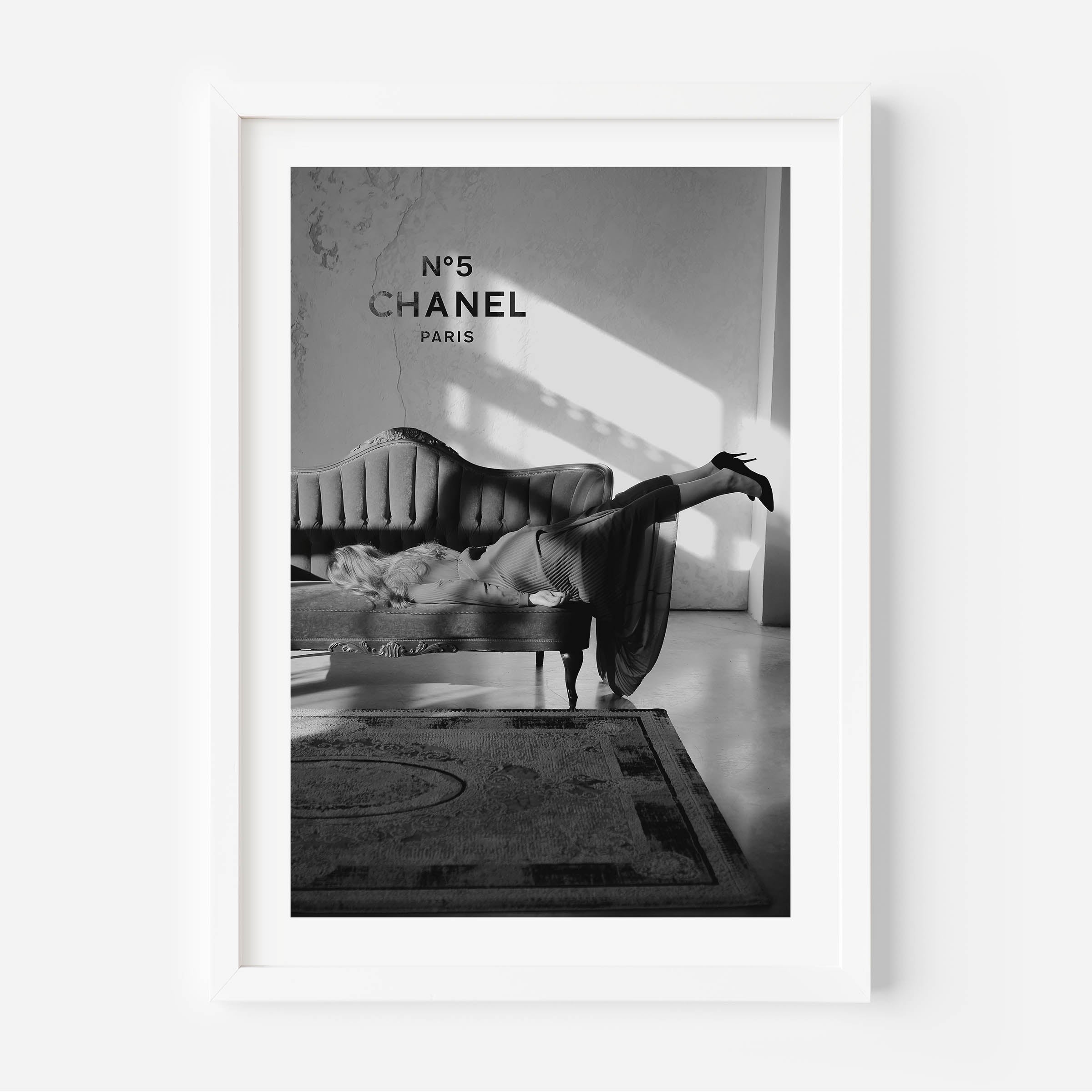black and white poster of a woman on a sofa with in the background chanel n5 on the wall